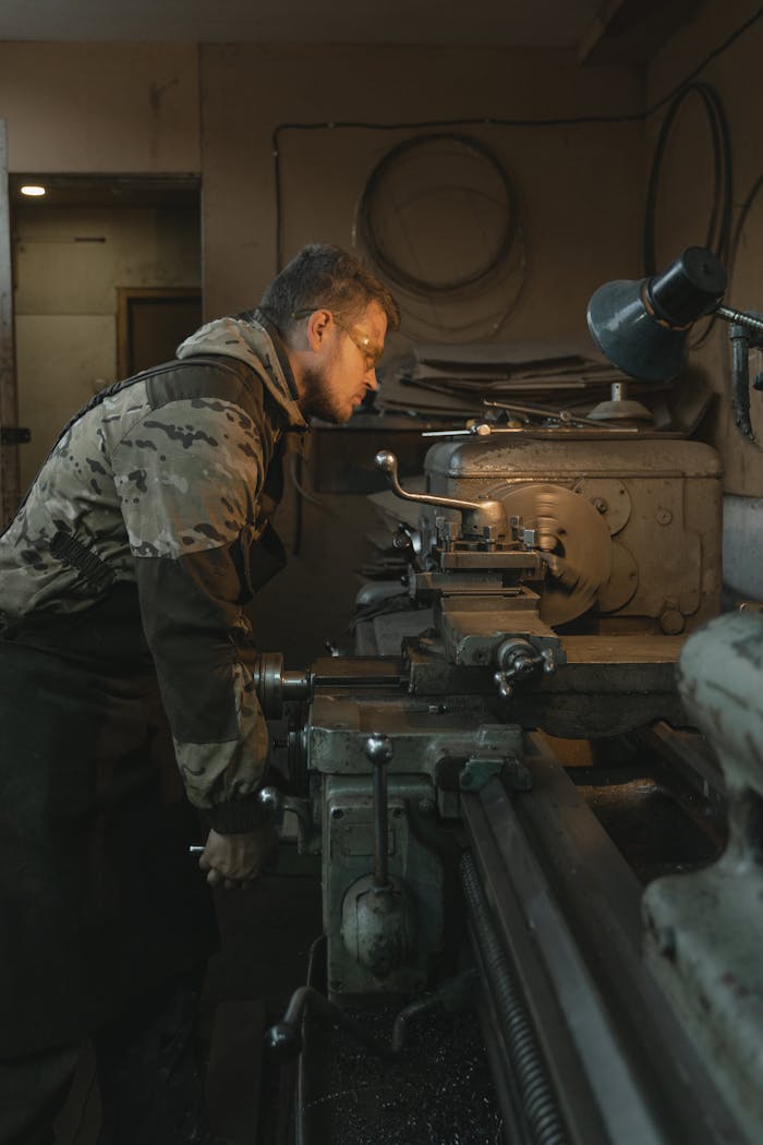 Artisan focused on a lathe machine, showcasing metalwork in a workshop setting.
